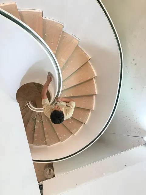 Top-down view of the spiral staircase during finishing, treads and curved steel stringer in progress